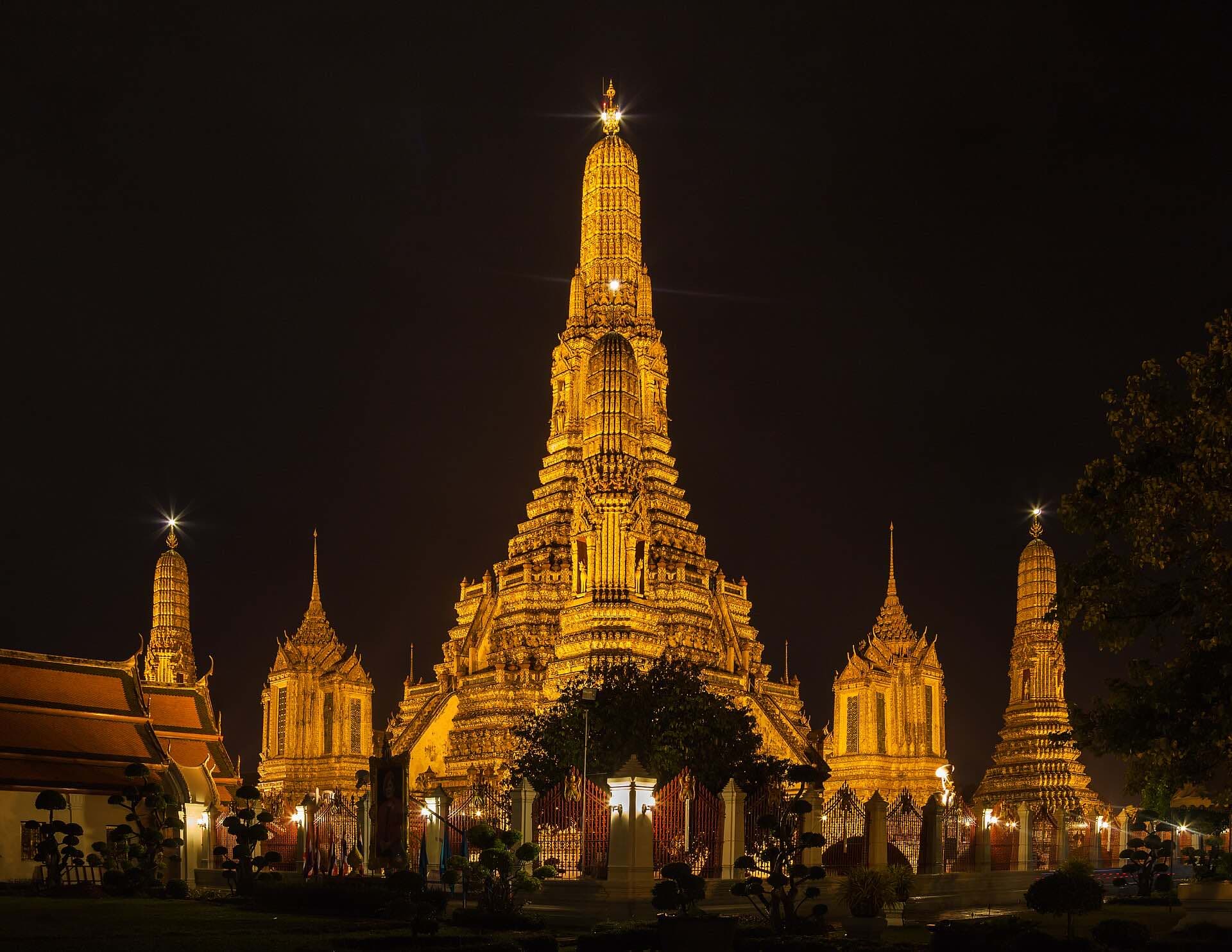 The spires of Wat Arun glowing gold at night
