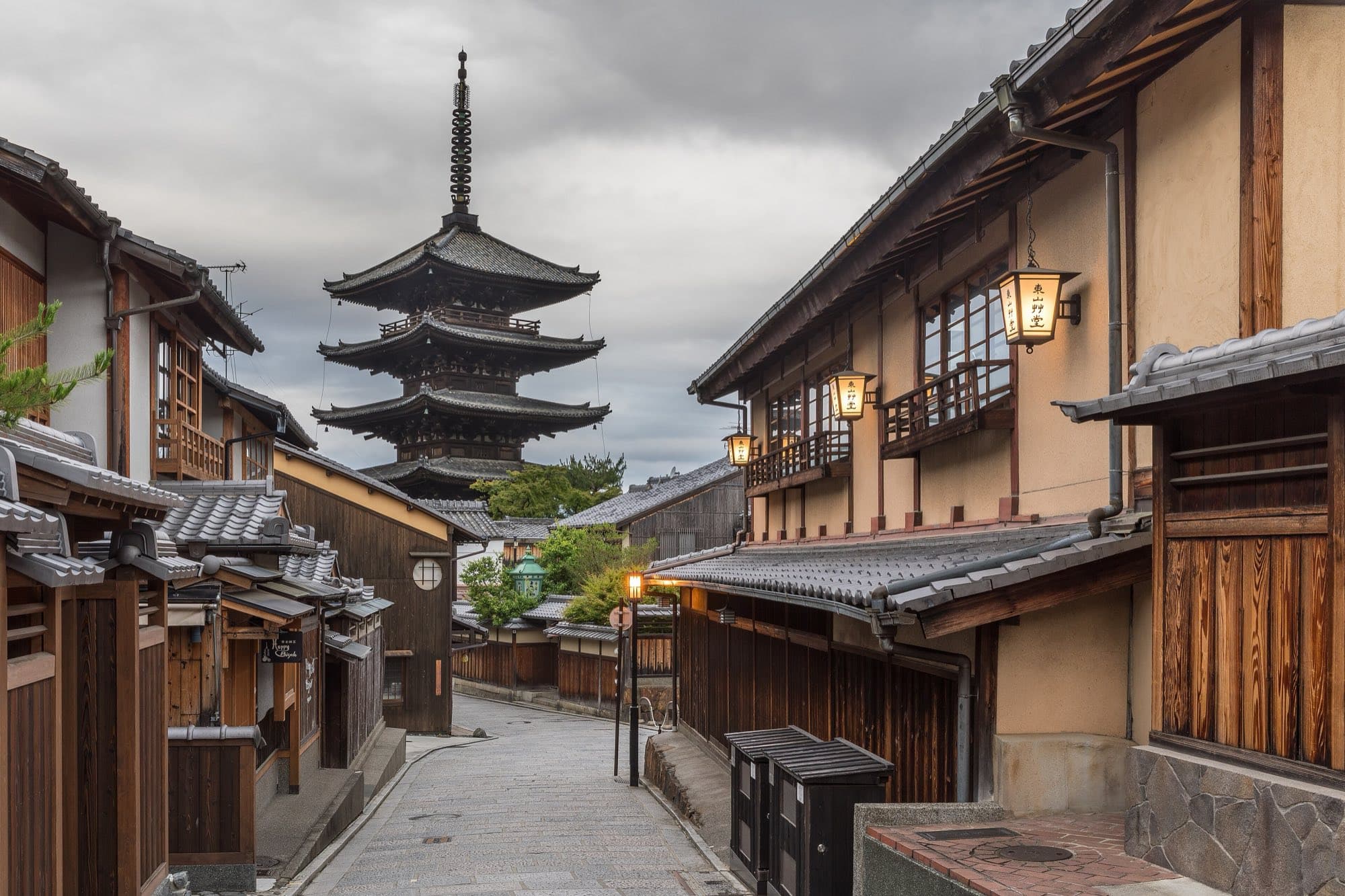 A quiet lantern-lit street in Kyoto leading to a five-story pagoda