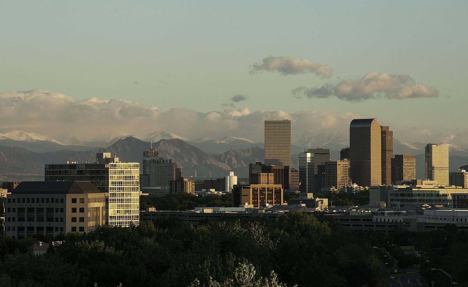 The Denver skyline at sunset with the Rocky Mountains behind it