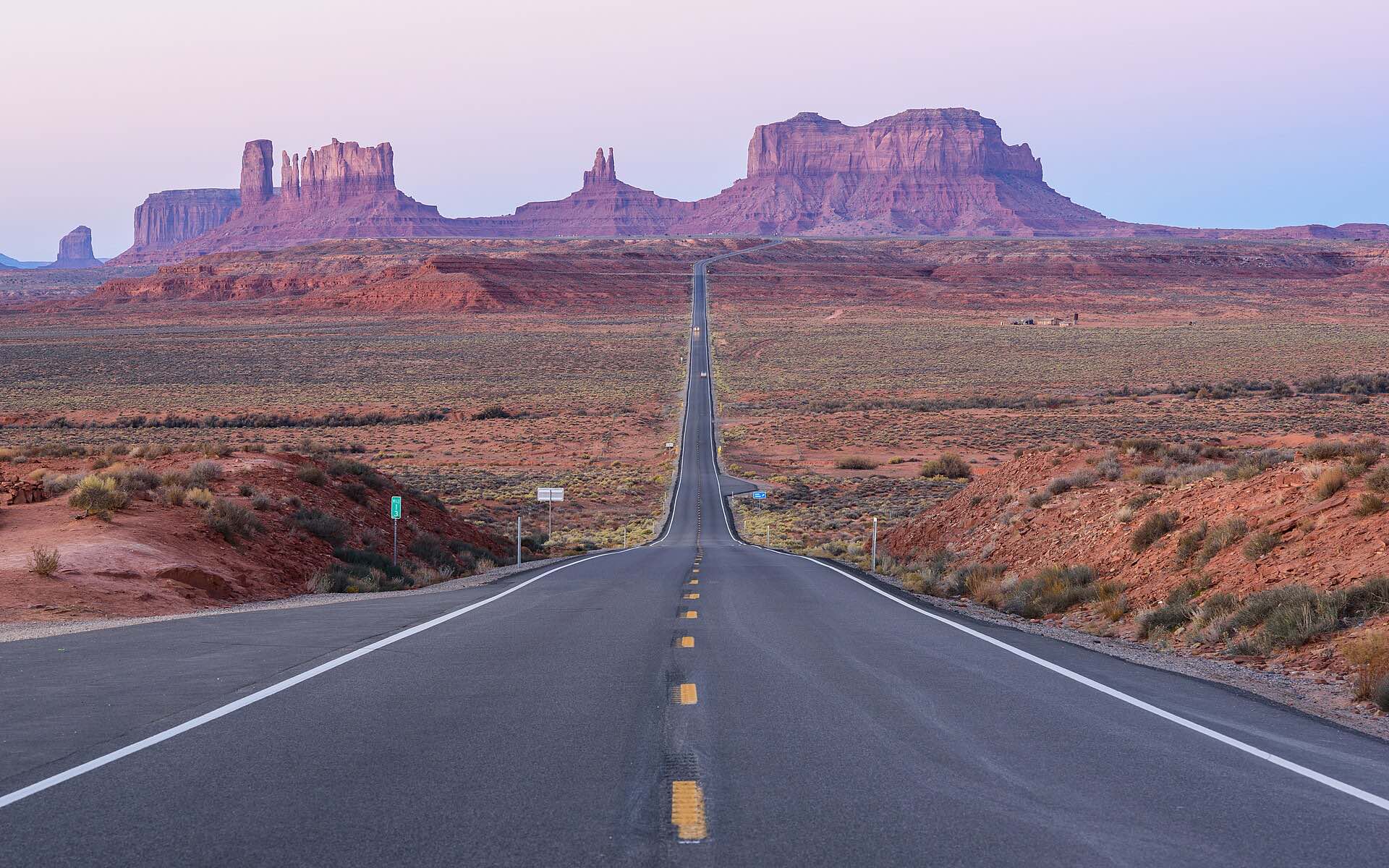 A straight desert road leading to the buttes of Monument Valley