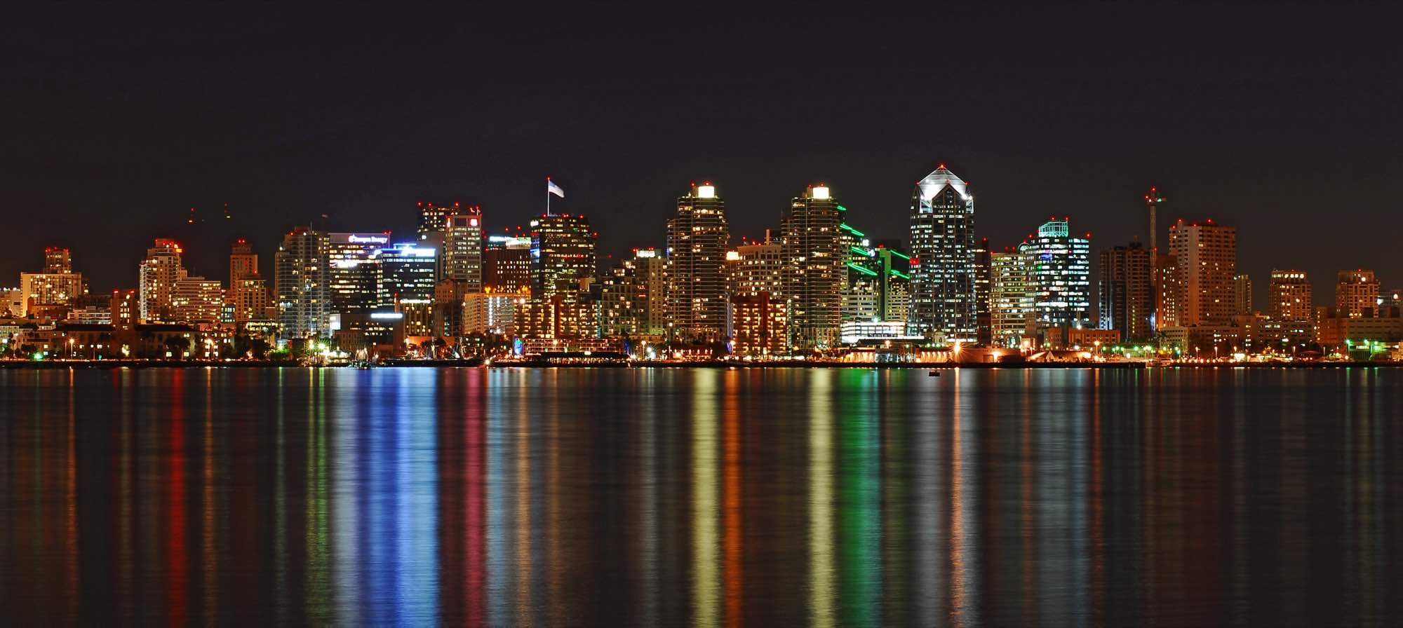 The San Diego skyline at night, its lights reflected in the bay