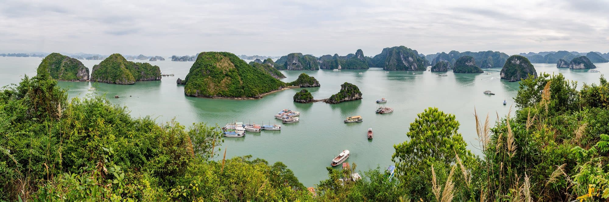 Limestone islands and boats in the green water of Hạ Long Bay